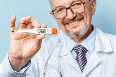 Portrait of a handsome senior doctor holding a thermometer in his hands, on a thermometer, the...