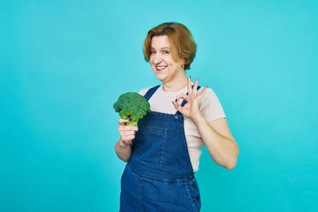 An aged woman is about to eat a vegetarian dish. Funny old woman on a broccoli diet. Healthy eating concept.の写真素材