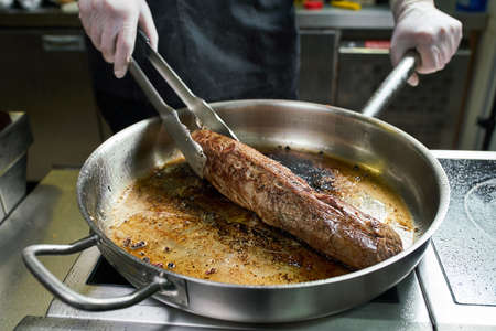 Cooking beef in a restaurant. steak and chef. closeup piece of roast meatの写真素材