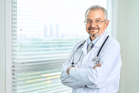 Cheerful mature doctor posing and smiling at camera, healthcare and medicine.の写真素材