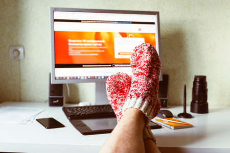 Self-employed work at home on a computer monitor. Study and work online, freelance, warm socks, winter, home comfort and relaxの写真素材
