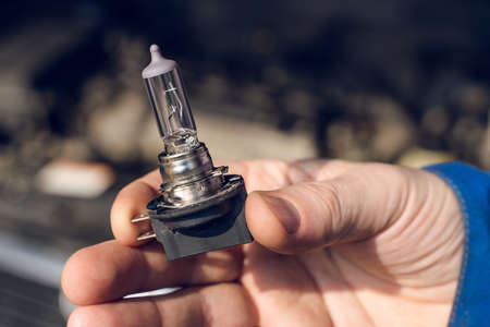 Car service men. Replacing a burnt out lamp in the car headlight