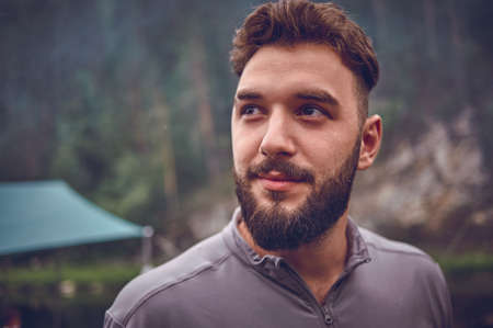 Portrait of a young, bearded man, on, against a background of wildlife. The concept of expedition, adventure and camping life.の写真素材