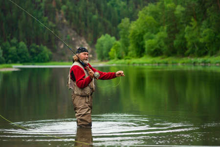 fly fishing angler makes cast while standing in water
