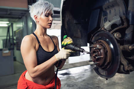 Sexy young woman repairing the car in a car serviceの写真素材