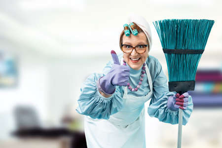 Portrait of a cleaning lady with a cleaning broom in hands. A cleaning lady in uniform is standing...