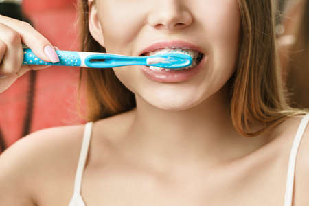 A young woman is brushing teeth in the bathroom. Reflection in the mirror