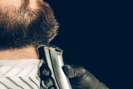Barbershop client. Man getting his beard trimmed with electric razor