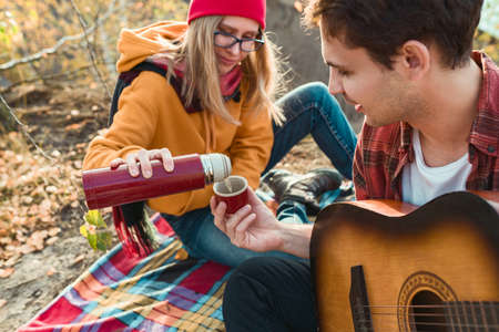 A couple are resting in nature, against the background of autumn trees and the river. Guy plays the...