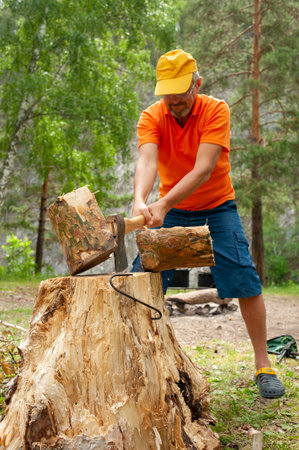 A man chops wood with an ax for a fire on a hike.の写真素材