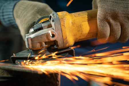 Locksmith in special clothes and goggles works in production. Metal processing with angle grinder....