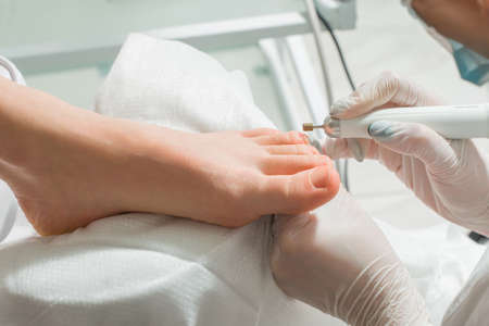 A Podiatrist doctor who takes care of a womans toenails. Cosmetic procedures of the feetの写真素材