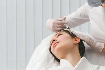 A woman getting a shot in the head at a cosmetology clinic. mesotherapy for hair growth.の写真素材