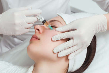 The cosmetologist makes anti-aging injections for the face to tighten and smooth out wrinkles on the...