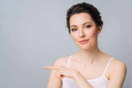 Young beautiful woman with perfect skin, gesturing to copy space. Cosmetology, beauty and spa concept.の写真素材