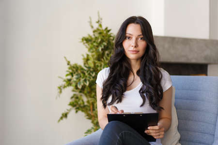 A young brunette fills out the information in the questionnaire. The woman looks into the camera and...