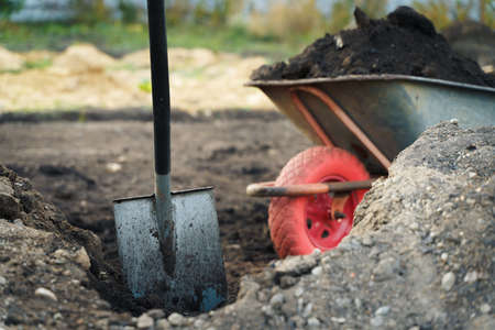 Working with garden tools, shovel and wheelbarrow on the site of a country house. Preparation for construction work.の写真素材