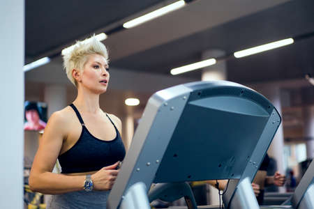 A young woman is engaged in fitness at the GYM. A woman on a treadmill.の写真素材