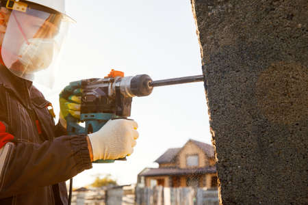A male installer works with a hammer drill. Construction works.の写真素材