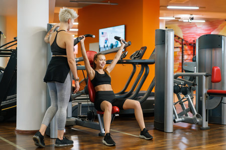 A young woman is doing fitness with a trainer at the GYMの写真素材