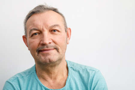 Portrait of a friendly elderly man with a mustache. A gray-haired man smiles looking at the camera