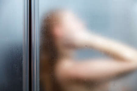 Rear view of a woman taking a shower in the bathroom. blurred image.の写真素材