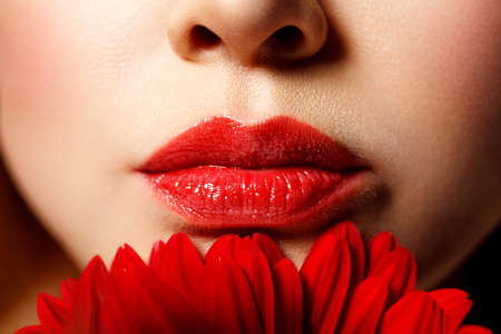 Sexy full female lips with red lipstick on the background of a flower. Aesthetic medicine services lip shape correction, lip augmentation.の写真素材