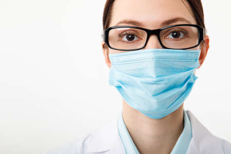 Portrait of a female doctor in a medical mask on a white backgroundの写真素材