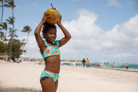 2022.03.14 Dominican Republic Punta Cana Bavaro. Portrait of a little girl on the beach with a coconut.のeditorial素材