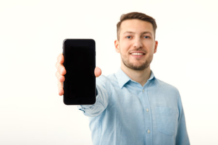 The man shows on the copyspace screen of the smartphone. Isolated on a white background.の写真素材