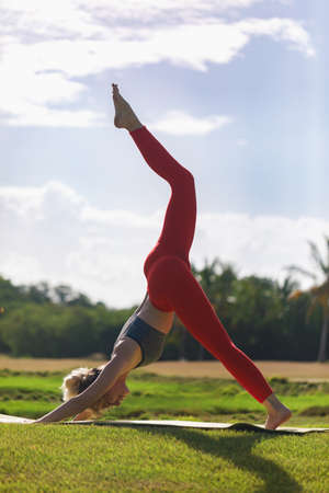A young woman practices yoga on the ocean coast during sunrise.の写真素材