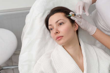 The doctor makes an injection into the head of a girl from hair loss. Hair treatment in a...