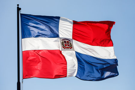 Dominican Republic flag waving against clear blue sky, close up, isolated.の写真素材