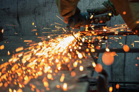 Industrial Metal worker Using Angle Grinder in Workshop with Flying Sparks