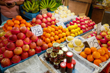 Apples, poncan oranges, lemons, and bottled jam at fruit stall in Philippines market with...