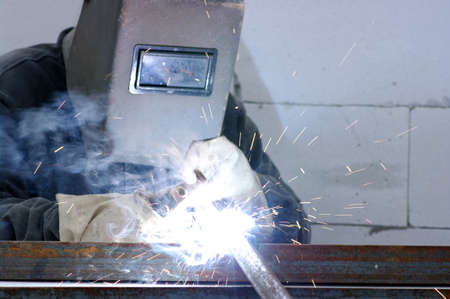welder worker welding metal. Bright electric arc and sparks 