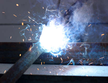 welder worker welding metal. Bright electric arc and sparks 