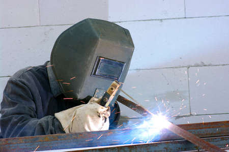 welder worker welding metal. Bright electric arc and sparks 