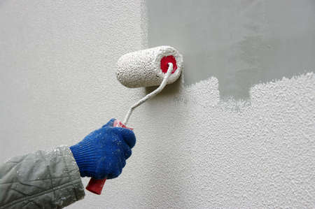 Hand painting a white wall with a paint rollerの写真素材