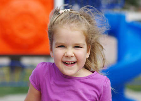 little girl on the playground. Happy smiling child playing on outdoor.