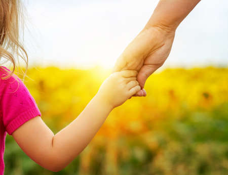 Hands of mother and daughter holding each other on fieldの写真素材