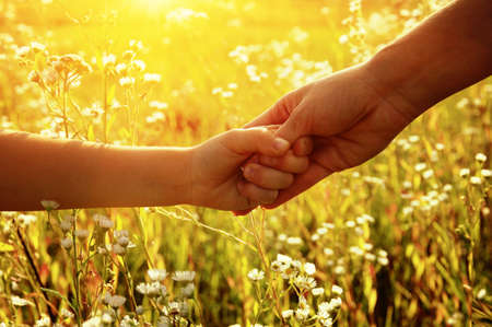 Hands of holding each other in field on road and sunの写真素材