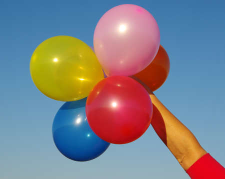 hand holding colorful balloons on sky