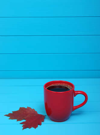 Autumn leaves, hot steaming cup of coffee  on wooden blue background.の写真素材