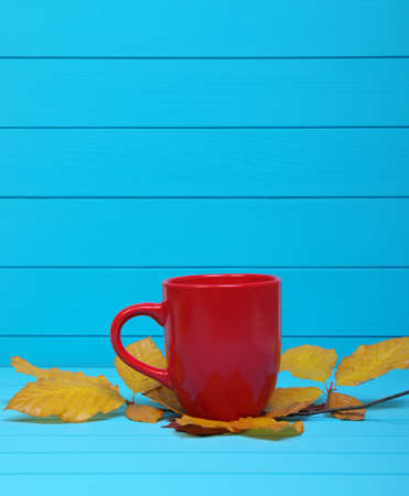Autumn leaves, hot steaming cup of coffee  on wooden blue background.の写真素材