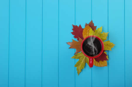 Autumn leaves, hot steaming cup of coffee  on wooden blue background.の写真素材