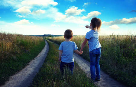 little boy and girl in the field looking the landscapeの写真素材