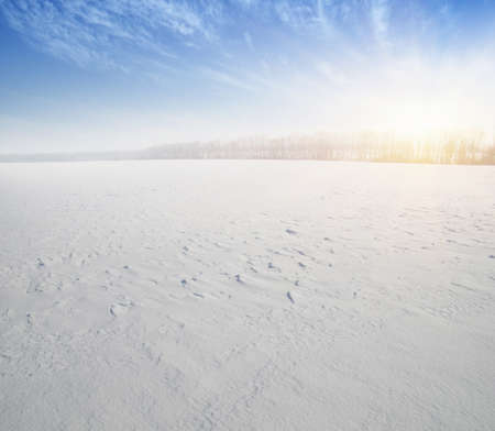 Winter landscape. Snowcovered fields on blue sky and sun.