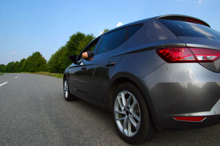 Car on asphalt road in nature. Man hand relaxing and enjoying road trip and sunny.の写真素材