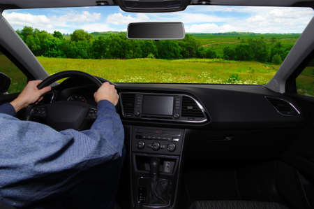 The man inside the car is driving along the road